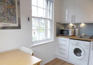 a kitchen with a washing machine and a microwave at Grassmarket Studio - Websters Land in Edinburgh