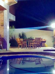 a table and chairs next to a swimming pool at night at Sobrado em Javary - 1 km do Lago in Miguel Pereira