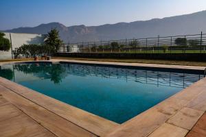 a swimming pool with blue water and mountains in the background at The Sariska Retreat in Thāna Ghāzi