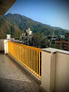a yellow fence on a balcony with mountains in the background at GreenDay Escapes Rishikesh in Rishīkesh