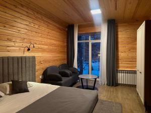 a bedroom with a bed and a chair and a window at Eastwood Hotel & Resort in Semey