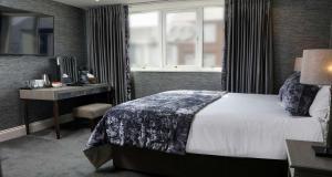 a bedroom with a bed and a desk and a window at The Lord Street Hotel; BW Signature Collection in Southport
