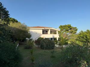 una grande casa bianca con alberi e cespugli di Casa Teresa a Porto Pino a Porto Pino