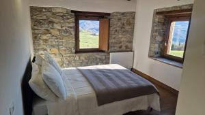 a bedroom with a bed with a stone wall and two windows at Campi dei sogni Bobbio in Bobbio