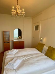 Un dormitorio con una gran cama blanca con una lámpara de araña. en Blue Bay Zandvoort, en Zandvoort