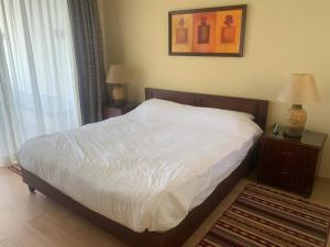 a bedroom with a bed with white sheets and two lamps at Marina Bliss-Seaside Retreat in Marsa Alam