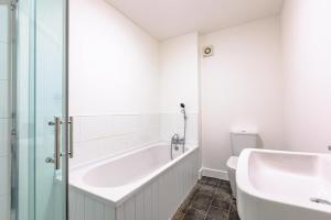 a bathroom with a tub and a toilet and a sink at Bridge House Court in Skinningrove