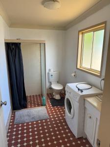 Un baño con lavadora y un inodoro. en 30 Elizabeth, en Sawtell 13 fotos más