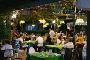 a group of people sitting at tables in a garden at night at Centro Vacanze Camping Spinnaker in Marina Palmense +31 photos