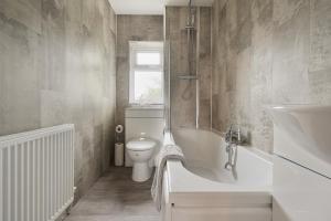 a bathroom with a toilet and a tub and a sink at St Abbs - Beautiful Home, EV, parking, garden in Hull +61 photos