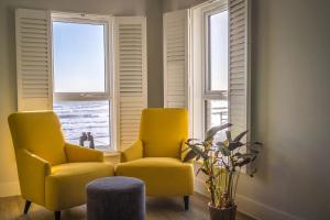 two yellow chairs in a room with windows at Wight Stone Luxury Townhouse - Breathtaking Views in Sandown