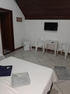 a room with two beds and a table and a tv at Pousada Villa's Hortelã in Passa Quatro