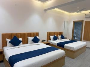 a bedroom with two beds with blue and white sheets at Hotel Taj Way by Jyoti Villa in Agra