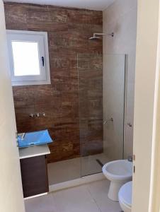 a bathroom with a glass shower and a toilet at Chalet Sebastian II in Pinamar +11 photos