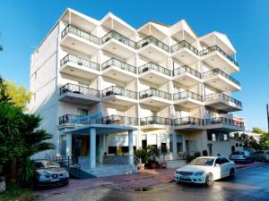 a white building with cars parked in front of it at Thomas Beach Hotel in Nea Makri