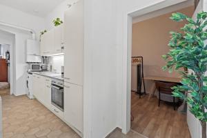 eine Küche mit weißen Schränken und einem Tisch mit einer Pflanze in der Unterkunft Spacious 2 Bedroom I 2 Minutes to Metro and Train Station in Wien + 16 Fotos