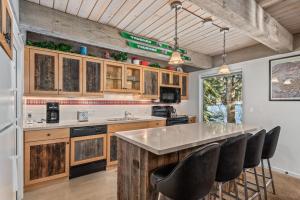 una cucina con armadi in legno e una grande isola con sedie nere di Chateau Eau Claire Unit 1, Stylish Condo Overlooking the River, Walking Distance to Downtown ad Aspen