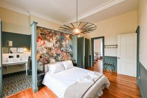 a bedroom with a bed and a painting on the wall at DE L'ART À LA MANIÈRE - Chambre d'Hôtes de Charme - 2 Suites Haut de Gamme - Idéal Couple & Famille - Piscine - Terrasse - Calme - 15min Saint-Émilion - EXPÉRIENCE Restauration d'Oeuvre d'Art in Branne