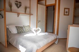 two swans sitting on a bed in a bedroom at O Cuend'U Lac in Osséja