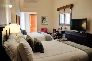 a bedroom with two beds and a flat screen tv at Casa Lucila Mazatlán Curamoria Collection in Mazatlán