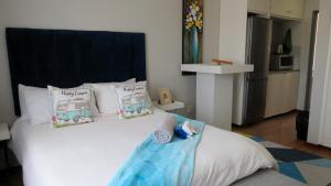 Un dormitorio con una gran cama blanca con almohadas. en Kombi Cove, en Ciudad del Cabo 2 fotos más
