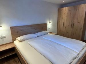 a bedroom with a large white bed with a wooden headboard at Pony-Ziegen-Hasen-Ranch Bichlbach in Bichlbach