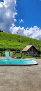 a swimming pool in front of a house with a hill at Pousada Villa's Hortelã in Passa Quatro +1 photo
