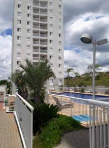 a tall building with a pool and a street light at Apartamento no portal dos ipes cajamar in Cajamar