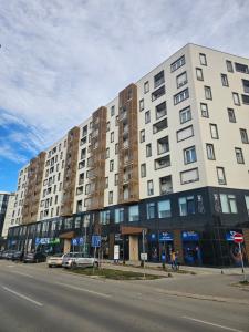 a large white building on a street with cars parked in front at Skyline Cozy Suites in Novi Sad