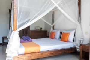 a bedroom with a canopy bed with colorful pillows at Villa Amber in Uluwatu