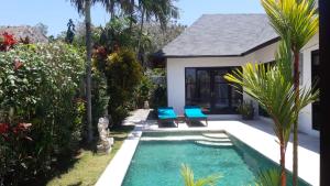 a pool with two blue chairs next to a house at Villa Amber in Uluwatu