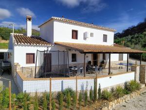a white house with a deck and a patio at Casa La Fuente in El Chorro