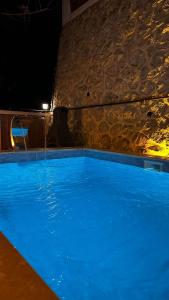 una grande piscina blu con un muro di pietra di Sıcak Havuzlu ve Jakuzili Villa 2 a Sakarya