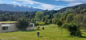 una casa en un campo con montañas al fondo en Una Morada en la Montaña, en El Bolsón