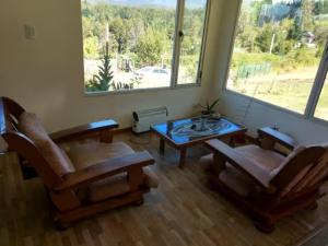 Una sala de estar con sillas y una mesa y una ventana. en Una Morada en la Montaña, en El Bolsón 36 fotos más