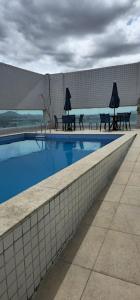 una piscina con tavoli e tavoli da picnic accanto a un edificio di Apartamento no Edifício Manhattan - Bairro Nobre de Caruaru a Caruaru