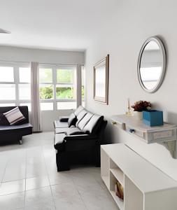 a living room with a black couch and a mirror at 11A - Apto c/2 QUARTOS, Sala e Cozinha completa,1WC, 1 Vaga, Roupa de Cama e VIVO FIBRA in Guarujá