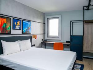 阿比让Ibis Styles Abidjan Plateau的卧室配有白色的床和橙色椅子