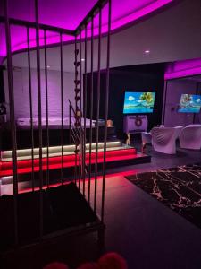 Zimmer mit einem Bett und einem TV mit violetten Lichtern in der Unterkunft Les Secrets Rooms in Hagondange