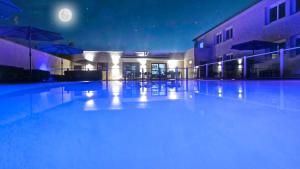an empty swimming pool at night with a full moon at Citotel Hôtel Le Capricorne in Marmande