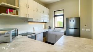 ハルガダにあるOllystays 4BR Townhouse Shared Pool El Gounaの白いキャビネットとステンレス製の冷蔵庫を備えたキッチン