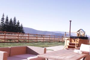 un patio avec une table en bois et une clôture en bois dans l'établissement Vanilla Mountain Resort, à Bălceşti