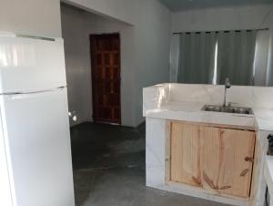 Una cocina con un refrigerador blanco y un fregadero. en Casa rosa, en Porto Seguro