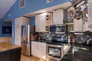 a kitchen with white cabinets and stainless steel appliances at Back Alley Apartment, Walk Downtown And Duke in Durham
