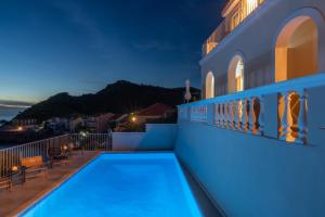 a villa with a swimming pool at night at Kanakis Apartments in Asos