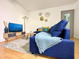 a living room with a blue couch and a tv at Le Bleu Soleil - à 2 min du métro - 7 min de Paris in Maisons-Alfort