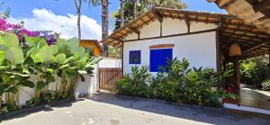 a small white house with a blue door at Suíte Kuta - Buddha House in Ilhabela