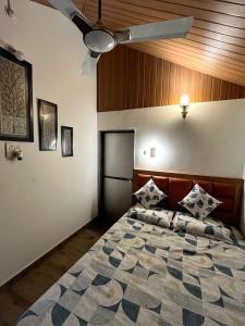 a bedroom with a bed with a ceiling fan at Rimzim's Tatvamasi - You In Nature in Kudal