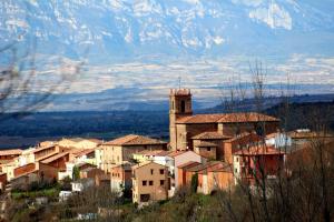 un pueblo con una torre de reloj y montañas en el fondo en Santa Coloma Apartamentos, en Santa Coloma 33 fotos más