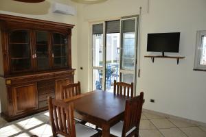a dining room with a wooden table and a tv at Casa vacanza Lui & Giò in Trecase